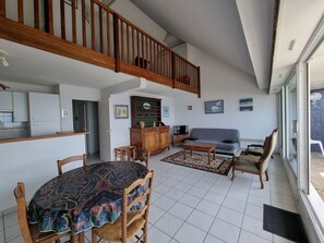Ein großzügiger Wohnbereich mit Esstisch, Sofa und Sesseln, ein Küchenbereich und ein Balkon mit Blick.