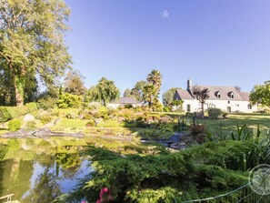 A serene garden with a pond, lush greenery, and a stone house. - Charming house with private garden, wifi, and parking in Sainte-Cécile (Sainte-Cécile)