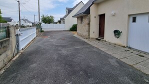 En smal gade med et hvidt hegn på den ene side og en bygning med en murstensfacade og en rødlakeret dør på den anden.