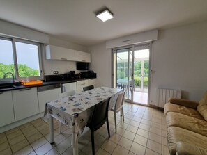 A compact kitchen with a dining table, a sofa, and a sliding glass door leading to a patio. - Renovated house near Kerfontaine Beach, 6 pers., pets allowed, 3 bedrooms (Sarzeau)