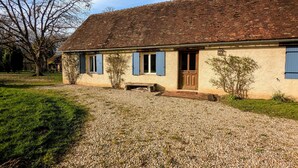 A single-story house with a sloped roof, a front porch, and a gravel driveway. - Charming accommodation with park and pond in Mers-sur-Indre (Mers-sur-Indre)