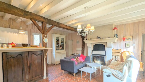 A rustic living room with a fireplace, a dining area with a wooden table, and a cozy seating arrangement. - Charming accommodation with park and pond in Mers-sur-Indre (Mers-sur-Indre)