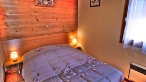 Ein Schlafzimmer mit einem hölzernen Kopfteil, einem Bett mit floraler Steppdecke, zwei Nachttischlampen und einem gerahmten Bild an der Wand.