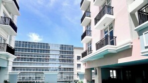 A modern hotel with a swimming pool, multiple balconies, and a glass facade building in the background. - Room-luxury 1-bedroom Stay at Saint Hono (Iloilo)