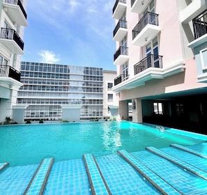 A modern hotel with a swimming pool, multiple balconies, and a glass facade building in the background. - Room-luxury 1-bedroom Stay at Saint Hono (Iloilo)