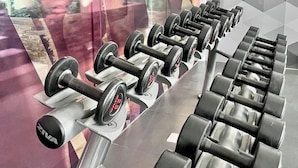 A row of black dumbbells on a gym bench with a mirrored wall reflecting a person. - Room-luxury 1-bedroom Stay at Saint Hono (Iloilo)