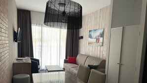 Een moderne hotelkamer met een eettafel, een bank en een groot raam met gordijnen.