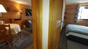 Un interno in legno con un letto, un tavolo con sedie, una lampada e un quadro appeso al muro.