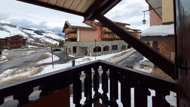 Vista da un balcone su un paesaggio montano innevato, con edifici sullo sfondo.