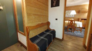 Un interno in legno con una panca, una testa di cervo incorniciata e un'area pranzo con tavolo e sedie.