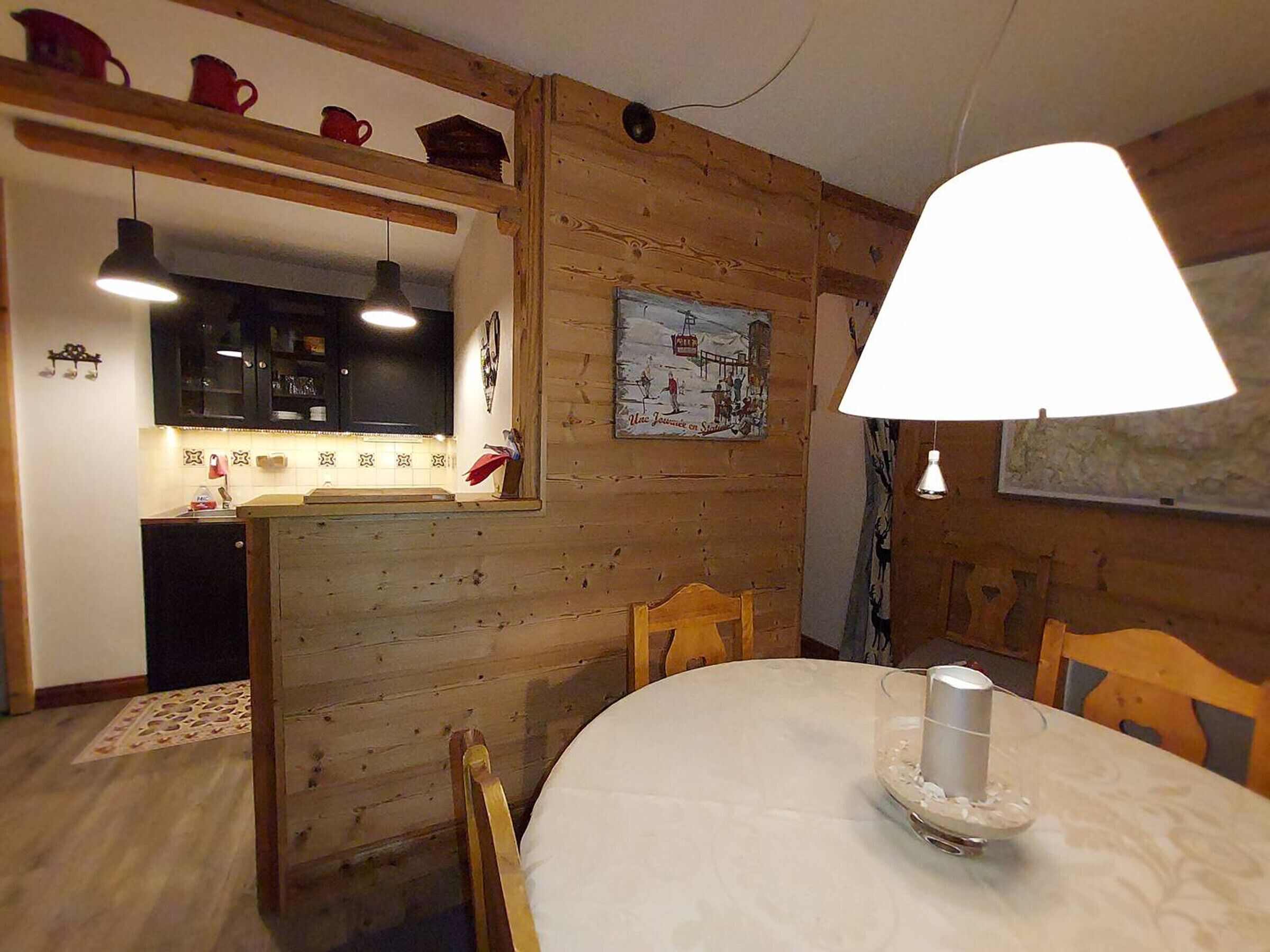 Een gezellige keuken met houten wanden, een eettafel met stoelen en een hanglamp.