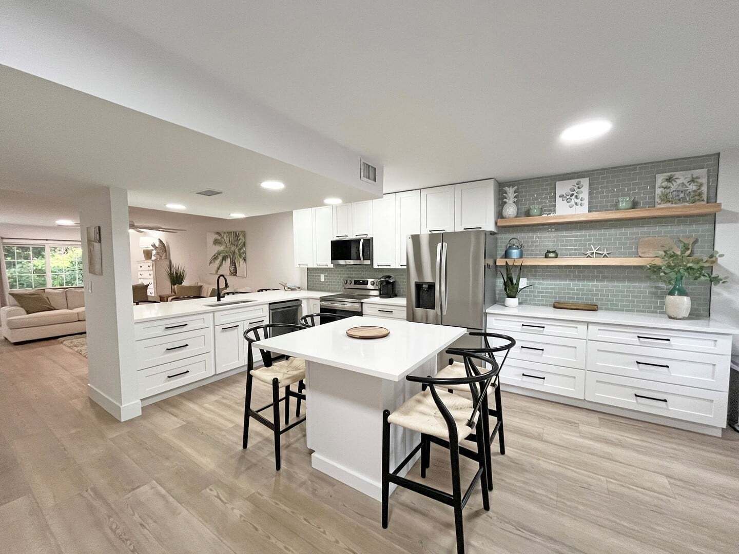 Une cuisine moderne avec des meubles blancs, un îlot central et un coin repas équipé de deux chaises.