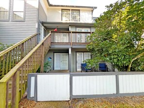 A two-story house with a front porch, a staircase, and a fenced yard. - Anastasia Oaks 104B Lo Tide (St. Augustine)