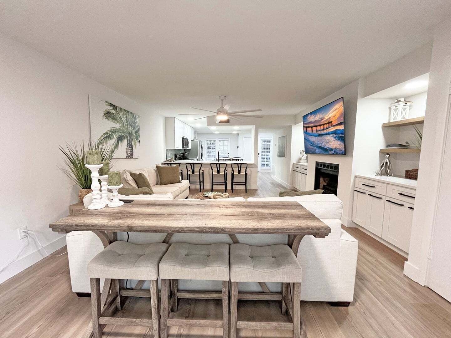 Une cuisine moderne dotée d’un îlot central, de meubles blancs et d’un coin repas avec une table en bois et des bancs rembourrés.