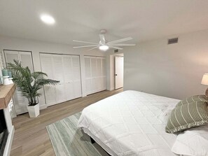 A bedroom with a bed, a ceiling fan, a potted plant, and a wardrobe. - Anastasia Oaks 104B Lo Tide (St. Augustine)