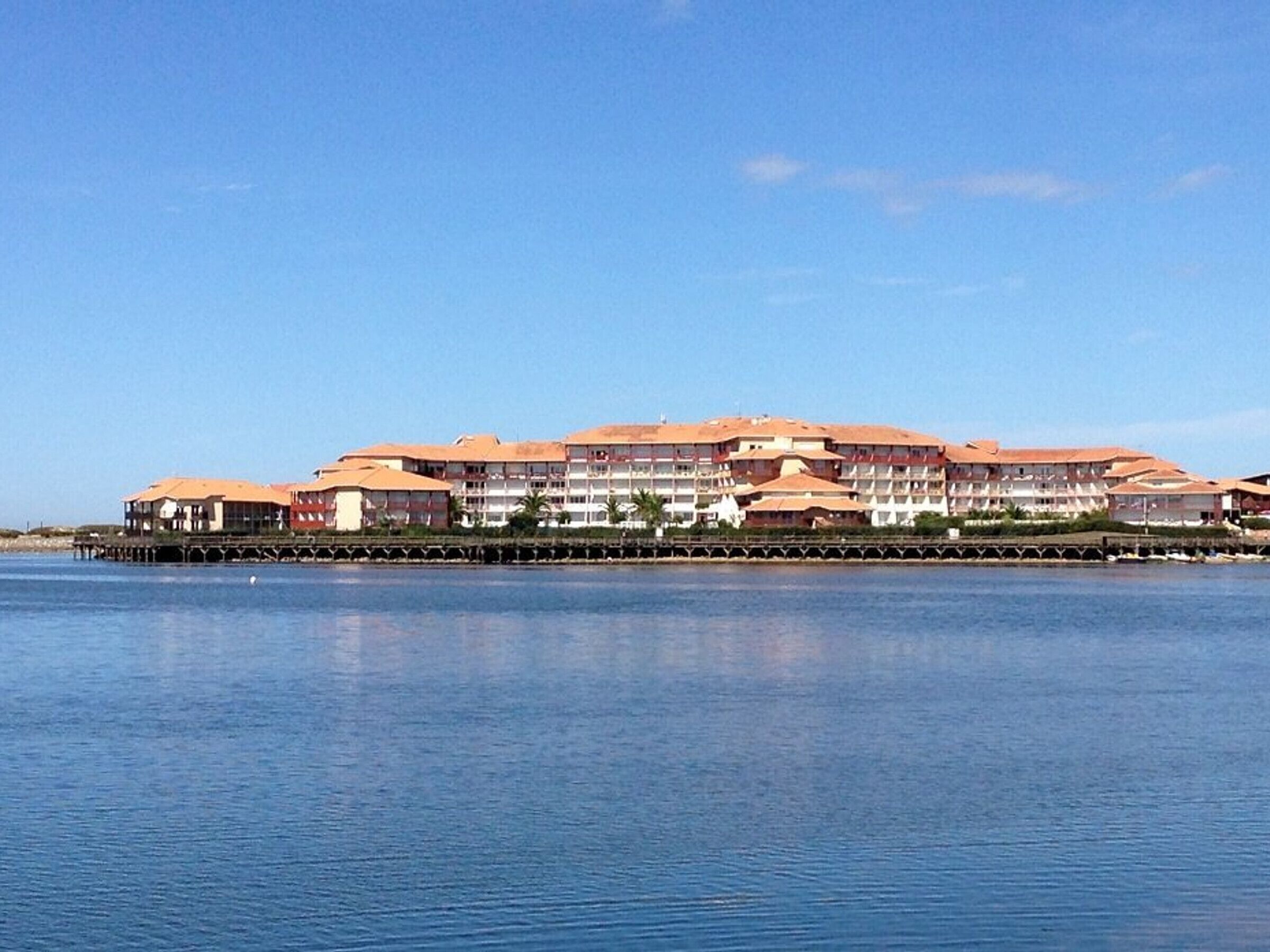 A large hotel with multiple balconies and a waterfront view.