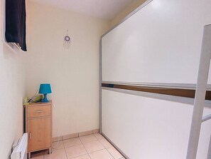 Ein kleiner, schmaler Raum mit einem Holzschrank, einer blauen Lampe und einem weißen Heizkörper.