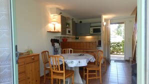 A compact kitchen with wooden cabinets, a dining table with chairs, and a microwave. - Air-conditioned duplex 2-bedroom with pool and parking - Le Lavandou (Le Lavandou)