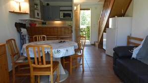 A compact kitchen with a dining table, chairs, and a refrigerator. - Air-conditioned duplex 2-bedroom with pool and parking - Le Lavandou (Le Lavandou)