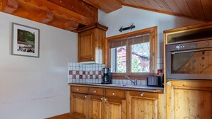 Una cocina con armarios de madera, salpicadero de azulejos, ventana con vistas y horno empotrado.