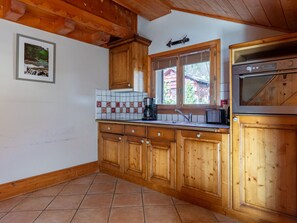 Eine Küche mit Holzausstattung, gefliestem Rücksprung, einem Fenster mit Blick und einem eingebauten Backofen.
