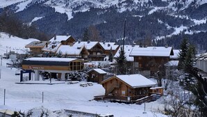 Un pueblo montañoso cubierto de nieve con edificios de madera, que incluye una estación de esquí y un restaurante llamado "Télévisage du GOLF".