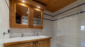 Un baño con armarios de madera, un lavamanos blanco y una cabina de ducha de vidrio.