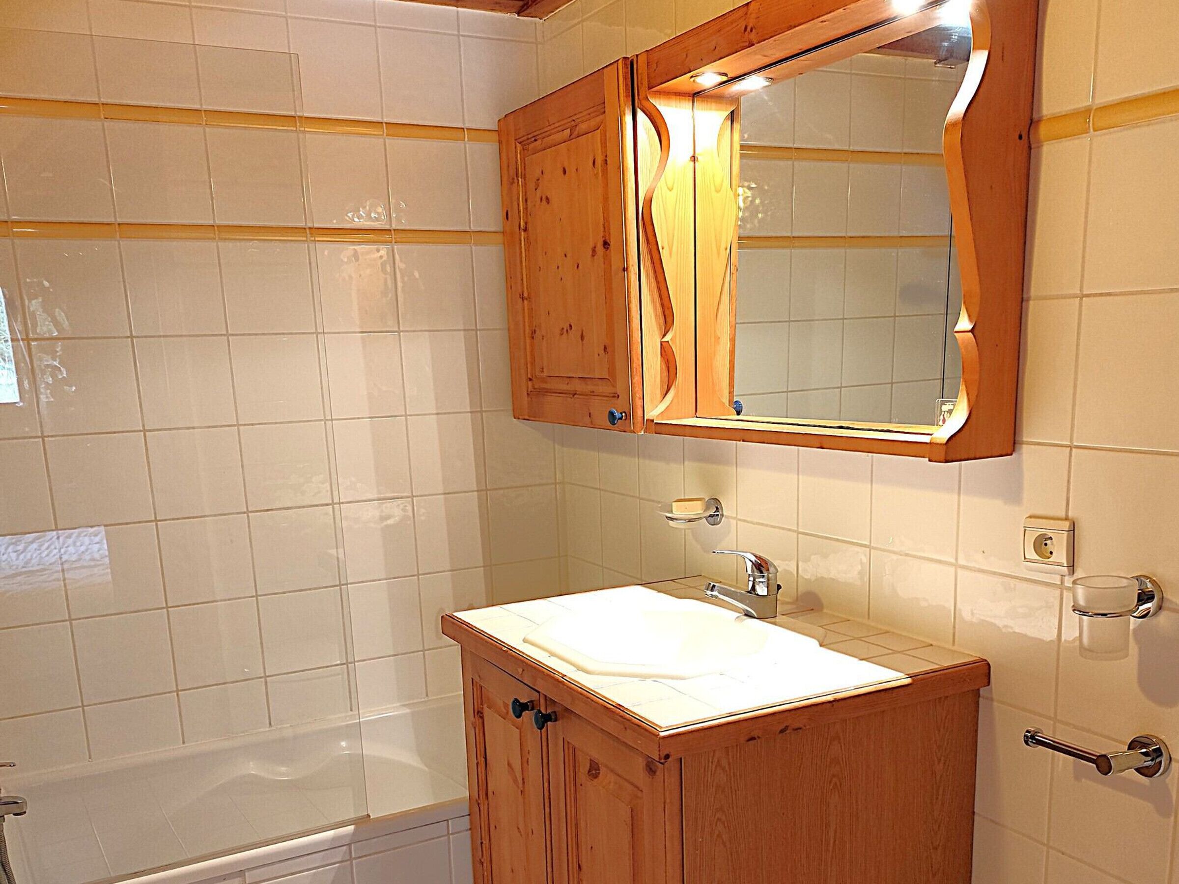 Ein Badezimmer mit einem Holzwaschtisch, einem weißen Waschbecken und einem Spiegel darüber.