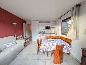 A compact living space with a dining area, kitchenette, and a sofa. - 4 pers. apartment facing slopes with south balcony, near ESF (Montgenèvre)