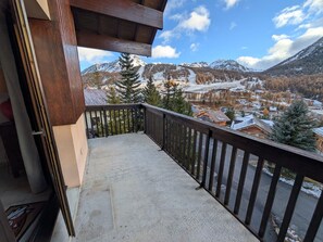 A balcony with a view of a snowy mountain landscape and a village below. - 4 pers. apartment facing slopes with south balcony, near ESF (Montgenèvre)