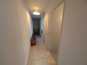 A narrow hallway with a tiled floor, a wooden bench, and a door on the right. - 4 pers. apartment facing slopes with south balcony, near ESF (Montgenèvre)