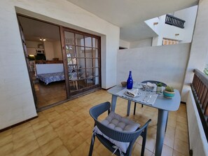 A balcony with a table set for dining, a chair, and a sliding glass door leading to a bedroom. - Studio in L'Escala 300m from beach, pool view (L'Escala)