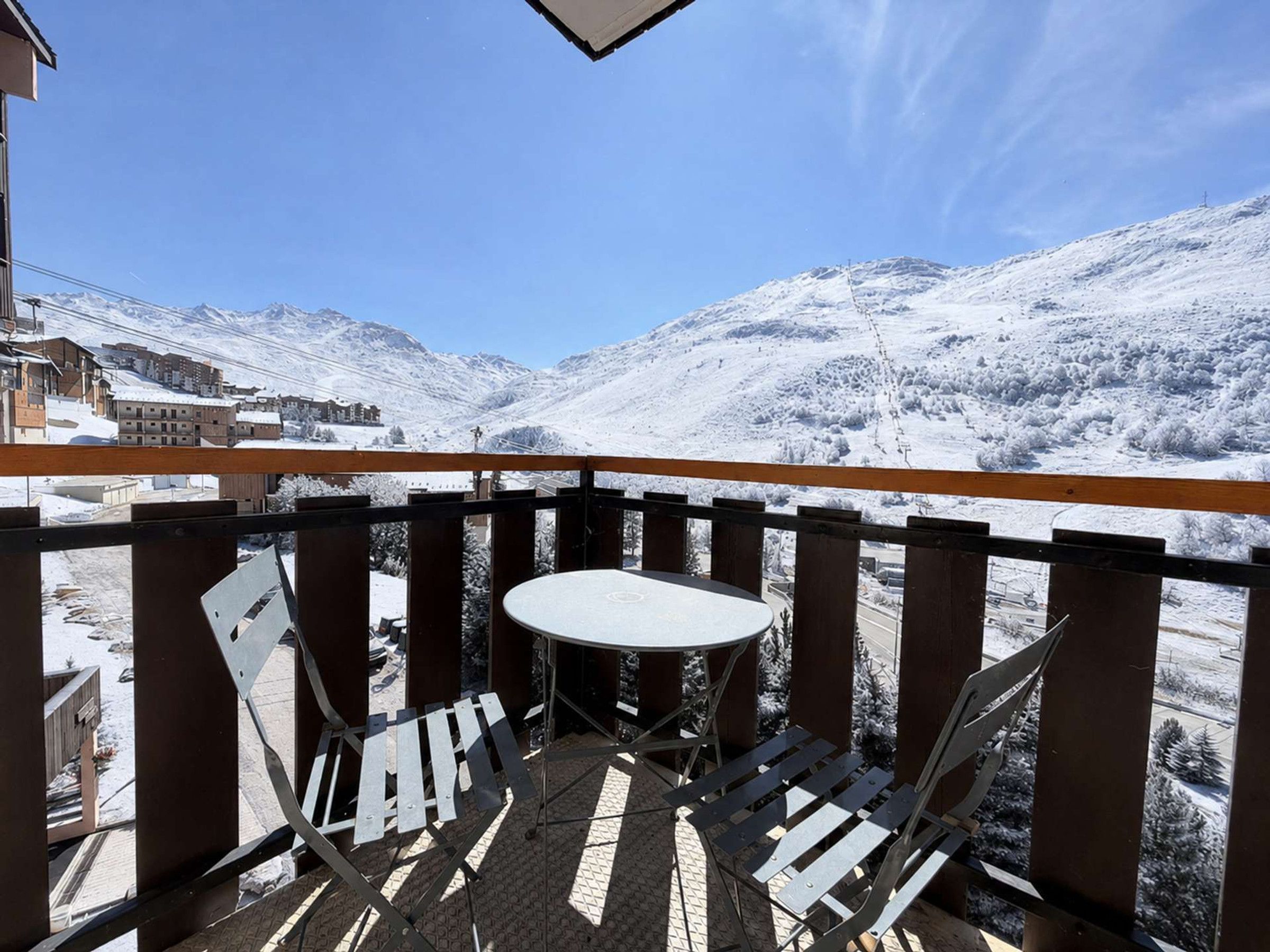 A balcony with a table and chairs, overlooking a snowy mountain landscape.
