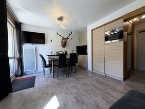 Eine moderne Küche mit eingebautem Ofen, ein Essbereich mit Tisch und Stühlen sowie ein großes Hirschgeweih an der Wand.