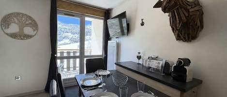 A dining area with a table set for four, a mounted television, and a decorative antler piece on the wall.