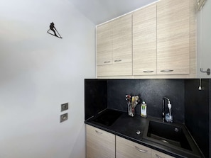 Eine Küche mit hellen Holzschränken, schwarzen Arbeitsplatten und einer schwarzen Spritzschutzwand.
