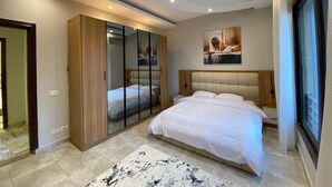 Ein modernes Schlafzimmer mit einem großen Bett, einem Kleiderschrank, einem Spiegel und einem Bild an der Wand.