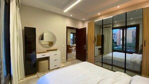 Ein modernes Schlafzimmer mit einem großen Bett, einem begehbaren Kleiderschrank, einem Spiegel und Blick durch eine Glastür.