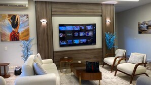Ein modernes Wohnzimmer mit Fernseher, bequemen Sitzmöglichkeiten und dekorativen Elementen.