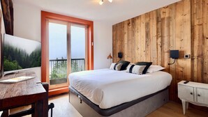 Ein Schlafzimmer mit einem großen Bett, einer Holzwand, einem Fernseher und einem Balkon.