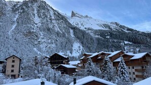 A mountain lodge with multiple wooden cabins, surrounded by snow-covered trees and a prominent mountain in the background. - Spacious Duplex Near Center - Pets Allowed (Pralognan-la-Vanoise)