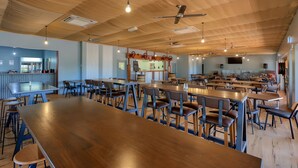 Ein geräumiges Restaurant mit hohen Holzbalkendecken, mehreren Tischen und Stühlen sowie einer Bar.