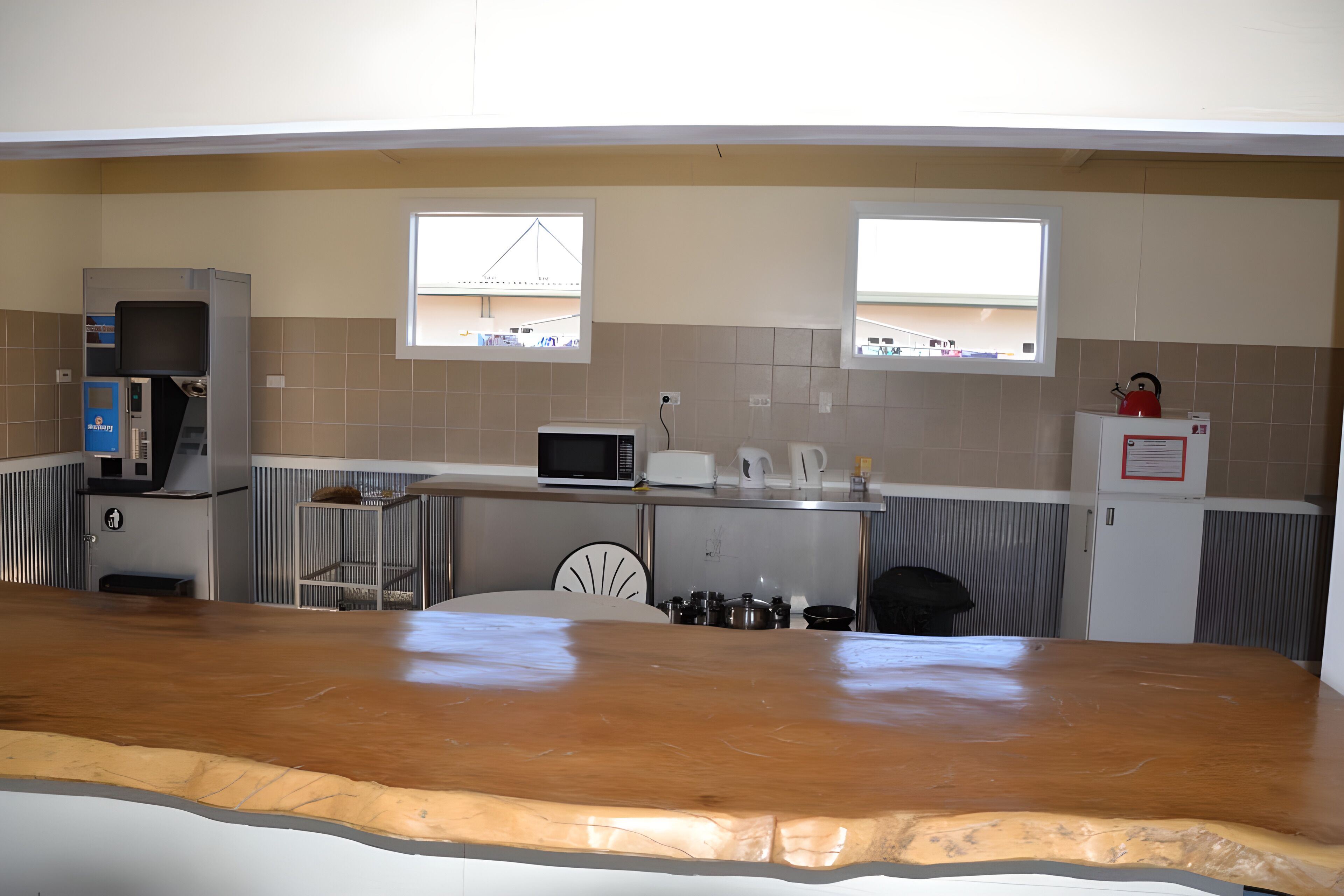Cocina equipada con microondas, hervidor de agua y refrigerador. Dos ventanas proporcionan luz natural.