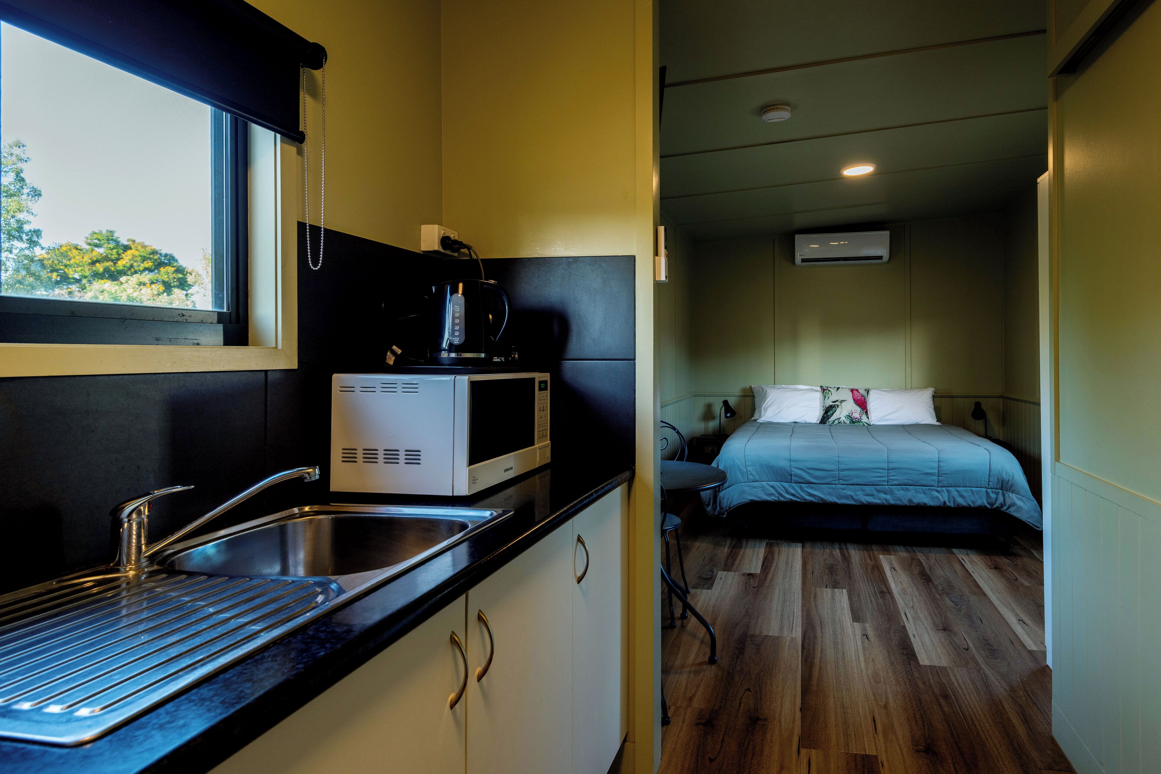 Una habitación pequeña con kitchenette, una cama y una ventana.