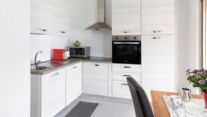 A modern kitchen with white cabinetry, a stainless steel sink, a microwave, a stove, and a coffee maker. - Lago 2 - Three Bedroom Apartment, Sleeps 8 (Oggebbio)