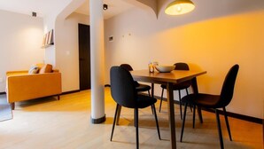 Ein modernes Wohnzimmer mit einer Couch, einem Esstisch mit Stühlen und einer Pendelleuchte.