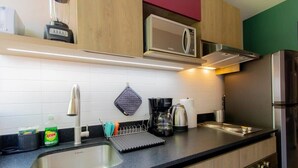 Eine moderne Küche mit Spüle aus Edelstahl, einer Mikrowelle, einer Kaffeemaschine und einem Wasserkocher.