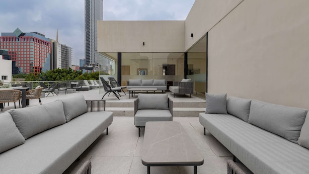 Terraza en la azotea con mobiliario exterior, incluyendo sofás y mesas, y vistas del horizonte urbano.
