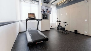 Una palestra con tapis roulant, cyclette e distributore d'acqua.