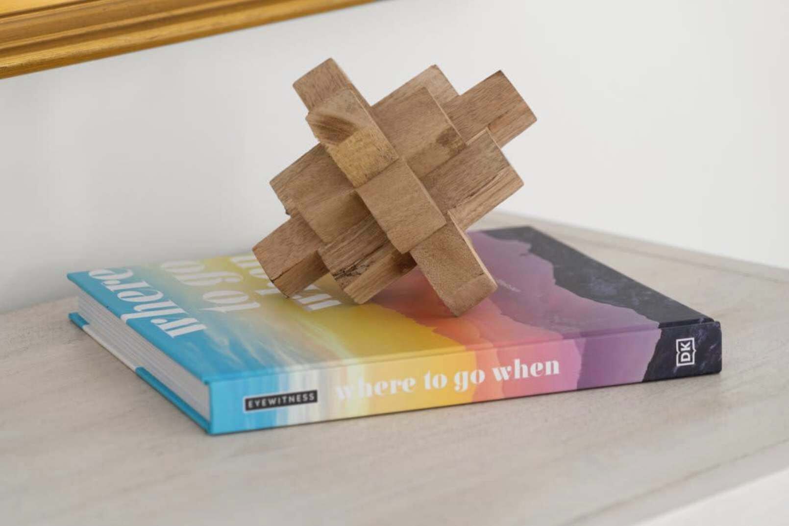 A book titled 'Where to go when' with a colorful cover, placed on a surface with a wooden block structure on top.